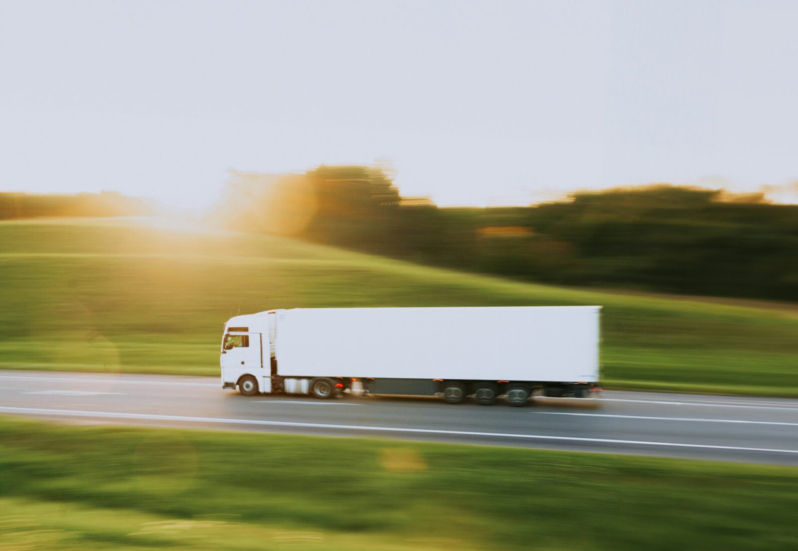 White commercial truck driving along the highway, showcasing the typical vehicle operated by holders of Commercial Driver's Licenses (CDL). A CDL is essential for anyone who drives commercial vehicles because it ensures they have the specialized skills to operate these often large, complex vehicles.